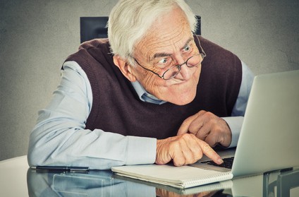 Photo of elderly man having difficulty with his laptop
